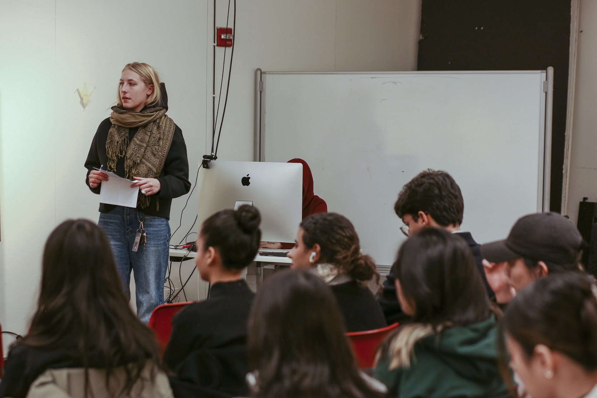 Student Cora Rafe (standing) holds an object while students are seated nearby